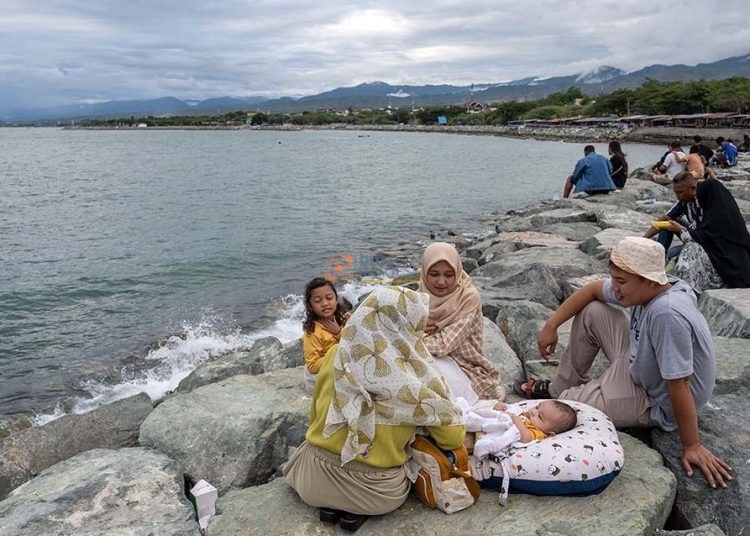 Pengunjung membawa bayinya saat berlibur di Pantai Kampung Nelayan di Palu, Sulawesi Tengah, Kamis (11/4/2024). Sejumlah tempat wisata pantai di wilayah itu ramai dikunjungi warga setempat untuk mengisi waktu liburan lebaran Idul Fitri. (bmzIMAGES/Basri Marzuki)