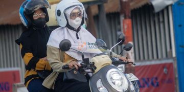 Pengendara sepeda motor mengenakan masker untuk menghindari paparan gas Sulfur Dioksida (SO2) yang telah mencapai status berbahaya hingga sangat berbahaya di Palu, Sulawesi Tengah, Selasa (23/4/2024). (bmzIMAGES/Basri Marzuki)