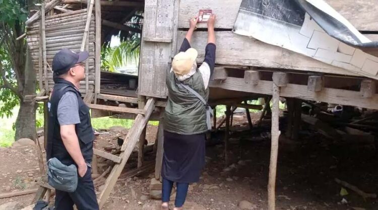 Petugas Pantarlih menempel stiker tanda Coklit di salatu rumah warga di Palu. (Foto: Bawaslu Kota Palu)