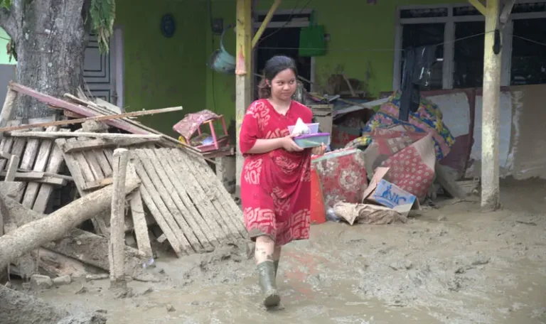 Warga membawa barangnya melintasi lumpur yang menggenangi rumahnya pascabanjir bandang di Desa Wombo, Kecamatan Tanantovea, Kabupaten Donggala, Sulawesi Tengah, Sabtu (31/5/2025). (bmzIMAGES/Basri Marzuki)