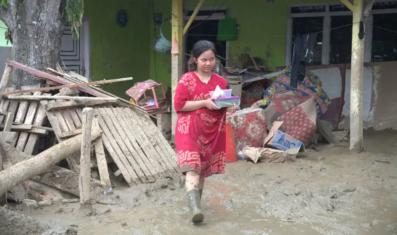 Warga membawa barangnya melintasi lumpur yang menggenangi rumahnya pascabanjir bandang di Desa Wombo, Kecamatan Tanantovea, Kabupaten Donggala, Sulawesi Tengah, Sabtu (31/5/2025). (bmzIMAGES/Basri Marzuki)