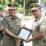 Gubernur Sulteng, Anwar Hafid (kiri) menyerahkan piagam penghargaan kepada Kasat Pol PP Kota Palu, Nathan Pagasongan pada Apel Kesiapsiagaan di parigi Moutong, Kamis (15/5/2025). (Foto: Satpol PP Kota Palu)