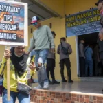 Warga membawa pamplet saat aksi damai jilid 2 menolak tambang di Kantor Camat Ulujadi, Kota PAlu, Selasa (10/5/2025). (Foto: bmzIMAGES/Basri Marzuki)