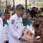 Kadis Kesehatan Kota Palu, dr. Rochmat Jasin (tengah) menyerahkan bantuan beras dari bazans Kota Palu ke warga di Tawaili, Rabu (4/6/2025). (Foto: Prokopim Stda Kota Palu/Jufri)